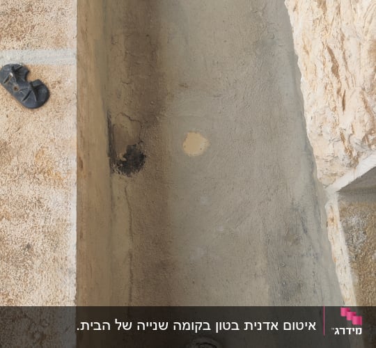 מריחת חומר איטום צמנטי בתעלה לצד קיר אבן חיצוני